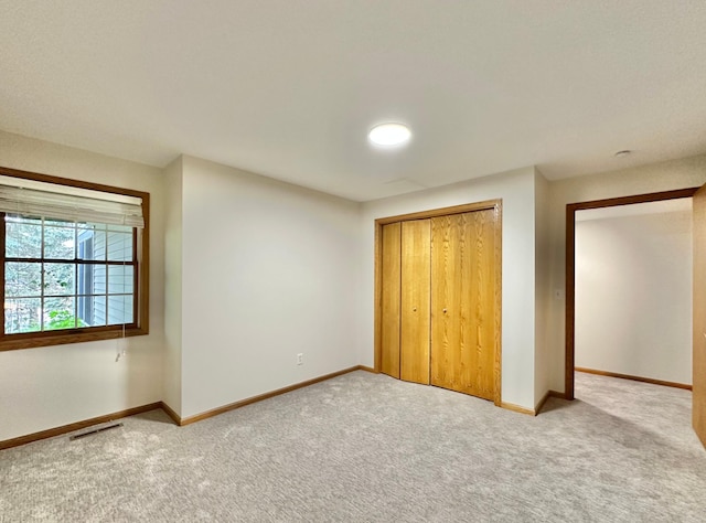 unfurnished bedroom featuring light colored carpet, a closet, and baseboards