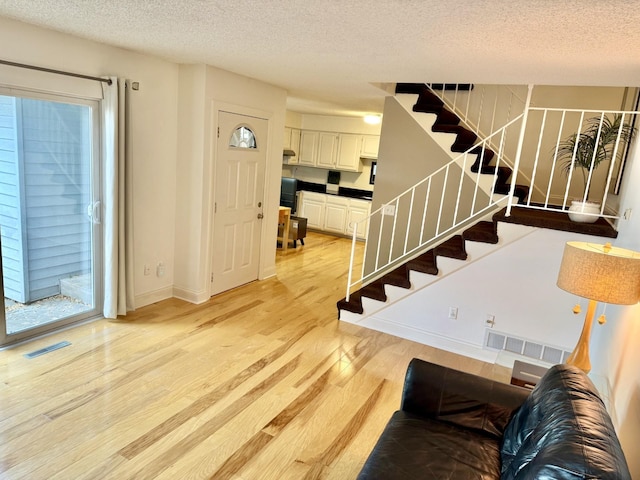 3568 Cloman Way, Inver Grove Heights, MN 55076 - living room with a textured ceiling, light wood-type flooring, stairway, healthy amount of natural light, and baseboards