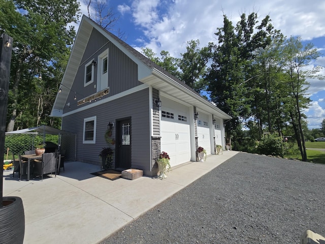 2293 57th Ave, East Farmington, WI 54020 - view of property exterior with gravel driveway, stone siding, and a garage