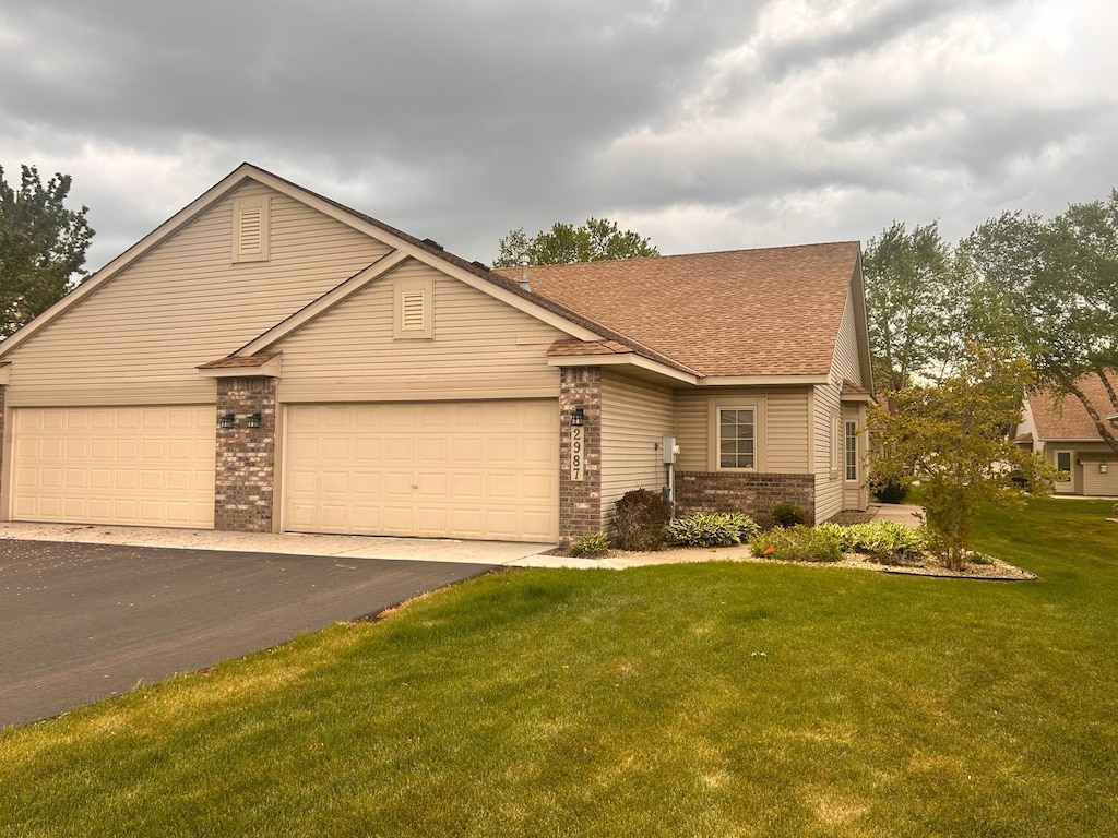 2987 Frattalone Ln, Little Canada, MN 55117 - view of front of house featuring brick siding, a front yard, asphalt driveway, roof with shingles, and an attached garage