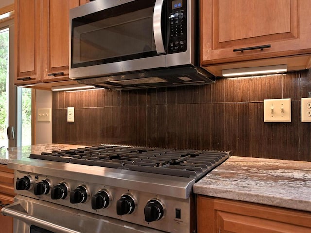 33272 Big Pine Trl, Grand Rapids, MN 55744 - kitchen featuring appliances with stainless steel finishes, decorative backsplash, brown cabinetry, and light stone countertops