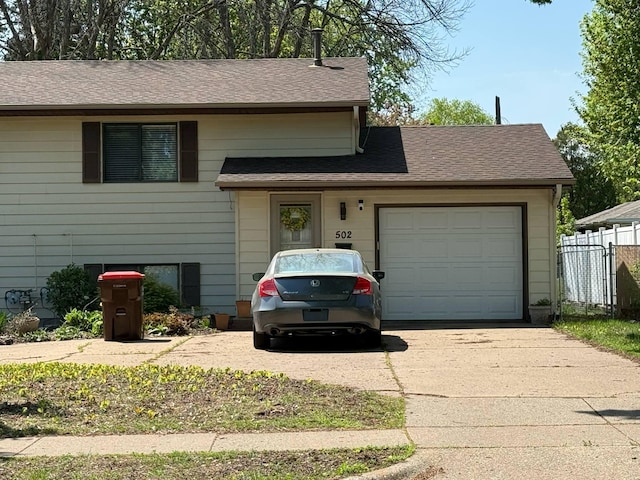 split level home featuring concrete driveway, an attached garage, and fence
