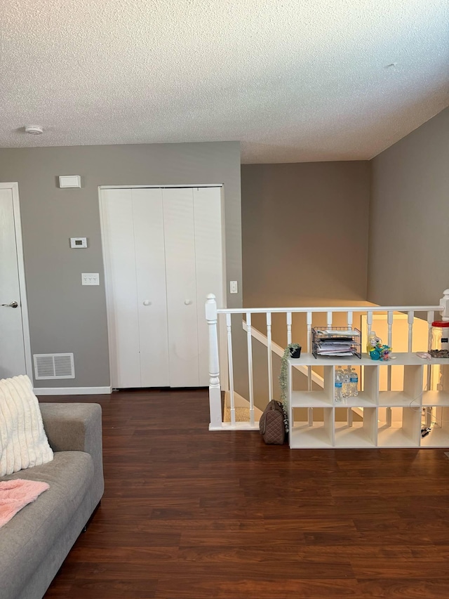 living area featuring wood finished floors, a textured ceiling, and baseboards