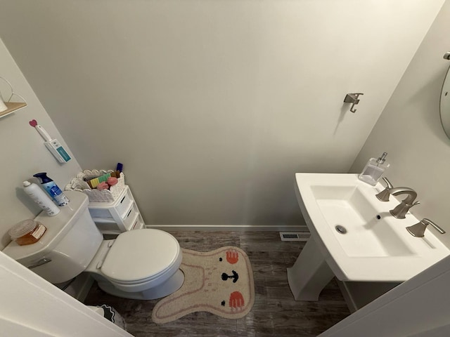 half bath with wood finished floors, a sink, and toilet