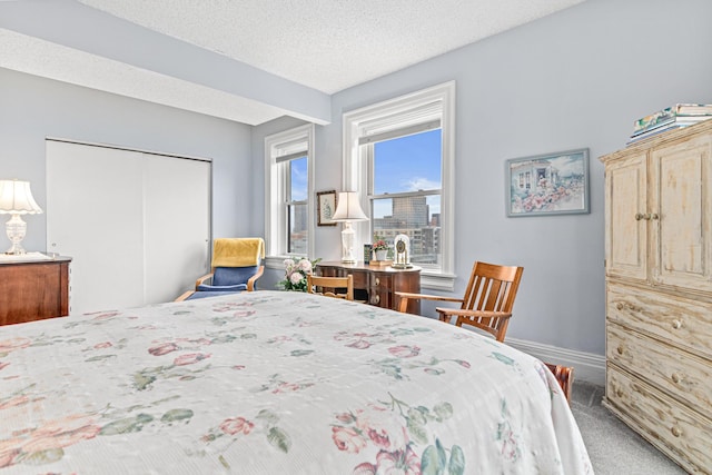 carpeted bedroom featuring baseboards, a closet, and a textured ceiling
