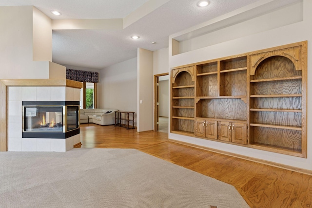 12124 Bluebird Cir NW, Coon Rapids, MN 55448 - unfurnished living room featuring light wood-style floors, recessed lighting, and a tiled fireplace