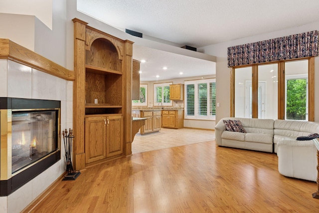 12124 Bluebird Cir NW, Coon Rapids, MN 55448 - living area with light wood-style floors, a tiled fireplace, and recessed lighting