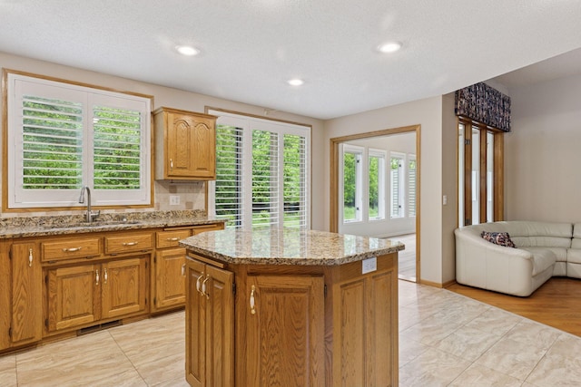 12124 Bluebird Cir NW, Coon Rapids, MN 55448 - kitchen with a sink, light stone counters, a kitchen island, recessed lighting, and open floor plan