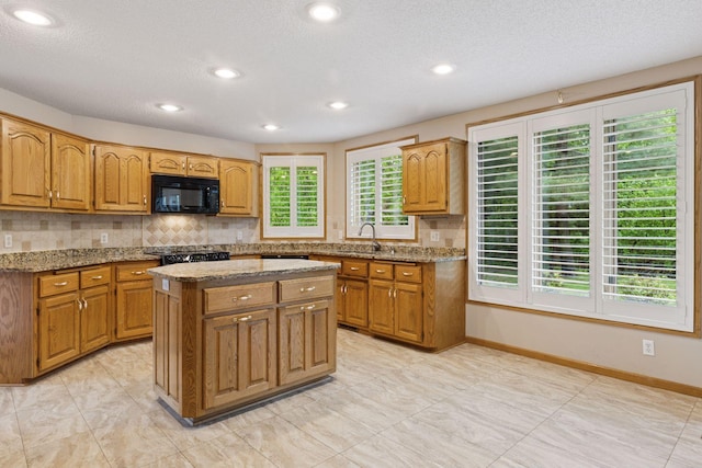 12124 Bluebird Cir NW, Coon Rapids, MN 55448 - kitchen with black microwave, decorative backsplash, a kitchen island, stone countertops, and baseboards