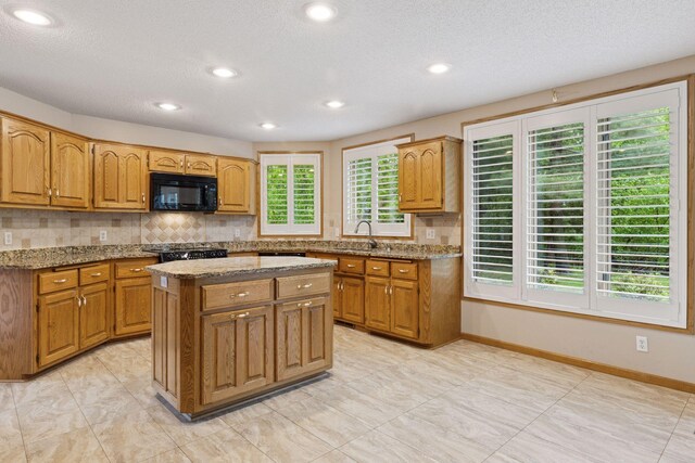 12124 Bluebird Cir NW, Coon Rapids, MN 55448 - kitchen featuring black microwave, tasteful backsplash, a center island, light stone counters, and recessed lighting