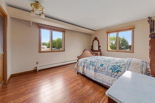 5440 Three Points Blvd Unit 536, Mound, MN 55364 - bedroom featuring multiple windows, a baseboard radiator, wood finished floors, baseboards, and a textured ceiling