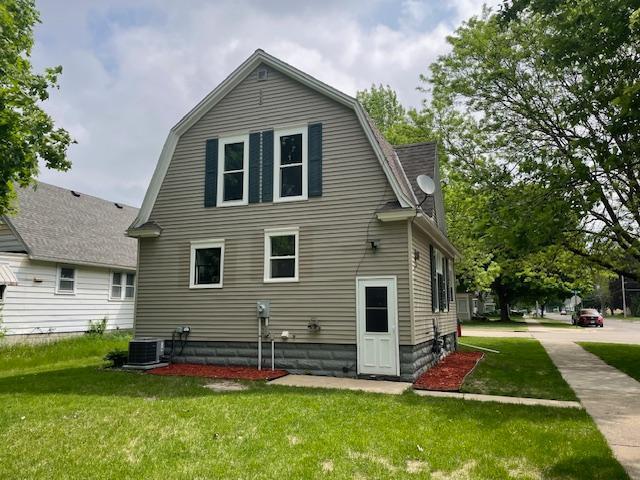 rear view of house with a yard, central AC, and a gambrel roof