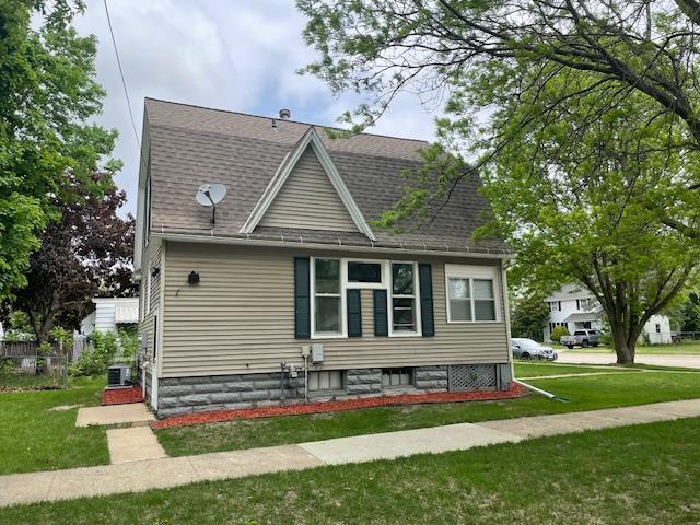 view of side of property with a lawn, roof with shingles, and cooling unit