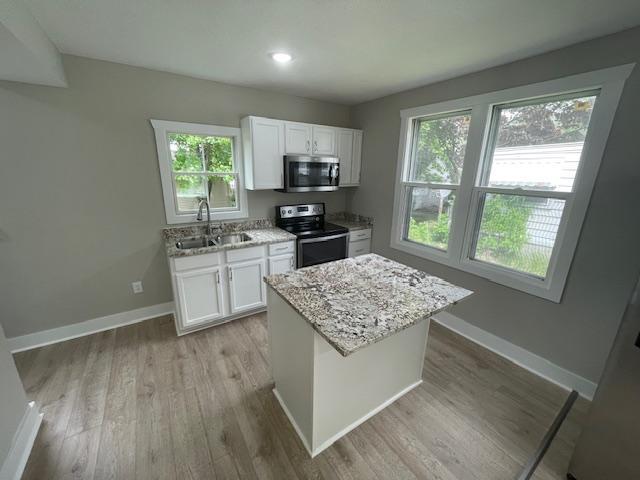 kitchen with appliances with stainless steel finishes, a sink, white cabinetry, light stone countertops, and recessed lighting