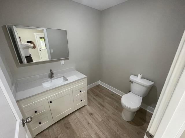 bathroom with wood finished floors, toilet, vanity, and baseboards