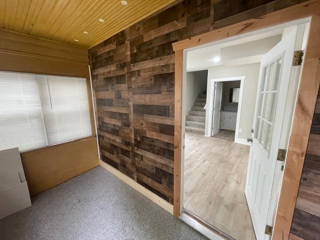 unfurnished room featuring wooden ceiling, wood walls, and stairs