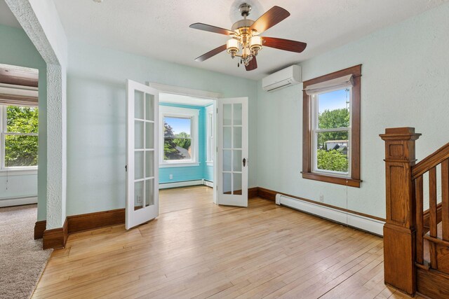 1125 James Ave, Saint Paul, MN 55105 - empty room with french doors, baseboard heating, an AC wall unit, and light wood-style flooring