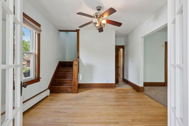 1125 James Ave, Saint Paul, MN 55105 - spare room featuring baseboard heating, light wood finished floors, ceiling fan, and stairway