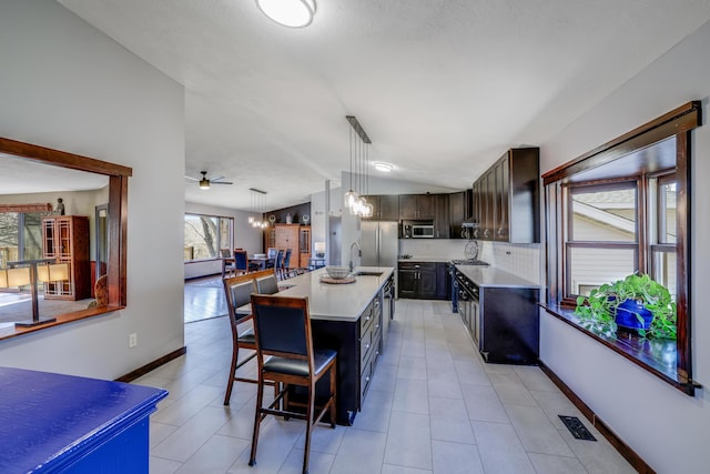 8678 Boiling Springs Ln, Shakopee, MN 55379 - kitchen with light countertops, stainless steel microwave, a breakfast bar, lofted ceiling, and an island with sink