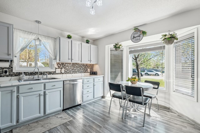 1905 125th Ave NE, Blaine, MN 55449 - kitchen with dishwasher, a sink, a textured ceiling, backsplash, and light wood finished floors