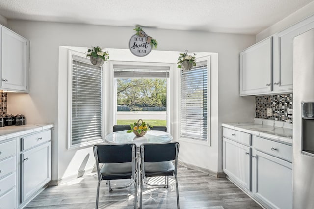 1905 125th Ave NE, Blaine, MN 55449 - dining space with light wood finished floors, a textured ceiling, and baseboards
