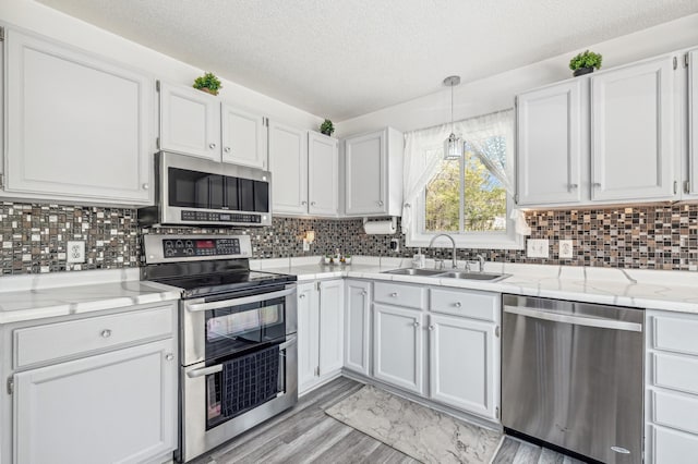 1905 125th Ave NE, Blaine, MN 55449 - kitchen featuring appliances with stainless steel finishes, a sink, a textured ceiling, white cabinets, and light wood-type flooring