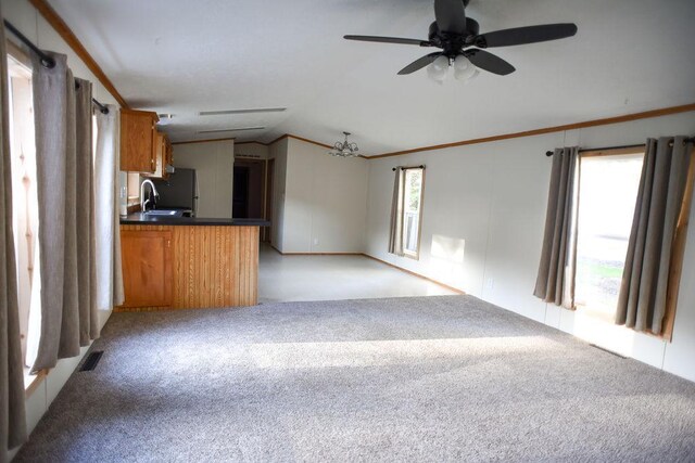 unfurnished living room featuring lofted ceiling, light carpet, a ceiling fan, a sink, and ornamental molding