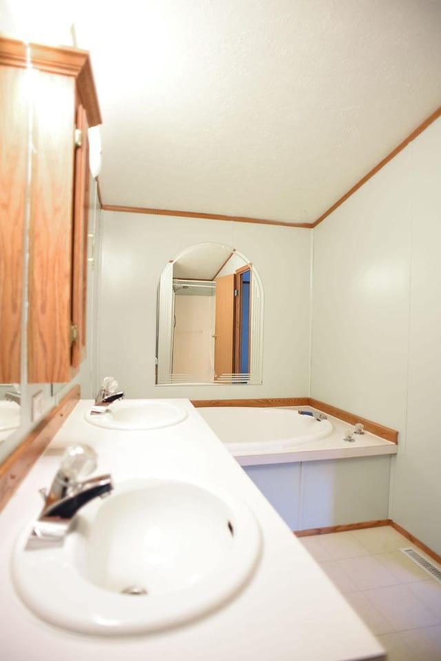 bathroom featuring a sink, ornamental molding, and a garden tub