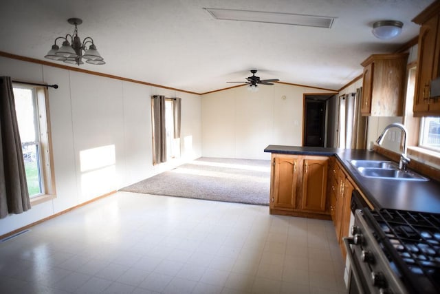 kitchen with stainless steel gas range oven, a sink, ornamental molding, brown cabinets, and lofted ceiling