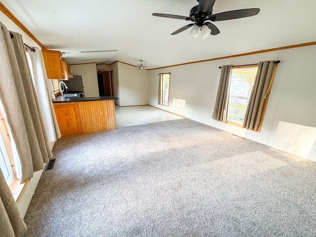 unfurnished living room featuring light carpet, plenty of natural light, a ceiling fan, and ornamental molding