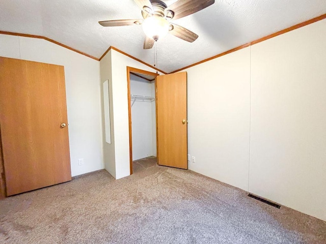 unfurnished bedroom with vaulted ceiling, carpet floors, ornamental molding, ceiling fan, and a textured ceiling