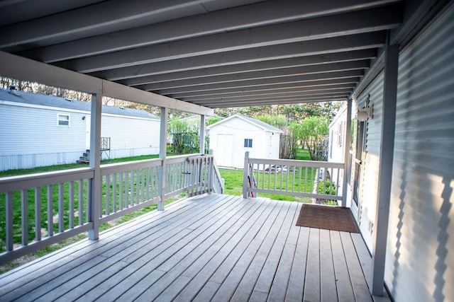 wooden deck featuring an outdoor structure and a storage unit