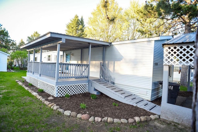 back of property featuring covered porch and a yard
