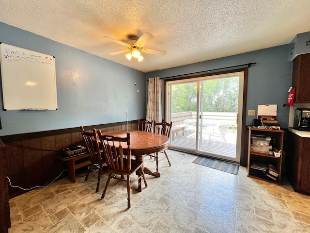 1416 13th Ave, Clarkfield, MN 56223 - dining space featuring ceiling fan, a textured ceiling, light stone finish floors, and a wainscoted wall