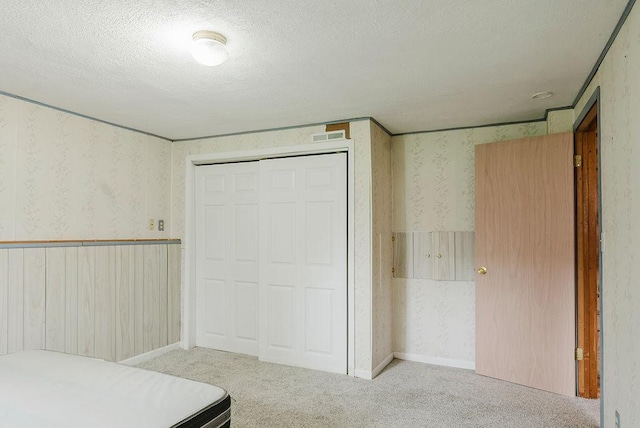 435 6th St, Cloquet, MN 55720 - unfurnished bedroom featuring wallpapered walls, carpet flooring, a textured ceiling, and a closet