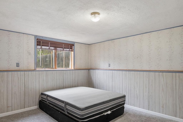 435 6th St, Cloquet, MN 55720 - bedroom featuring a textured ceiling, a wainscoted wall, wooden walls, baseboards, and wallpapered walls