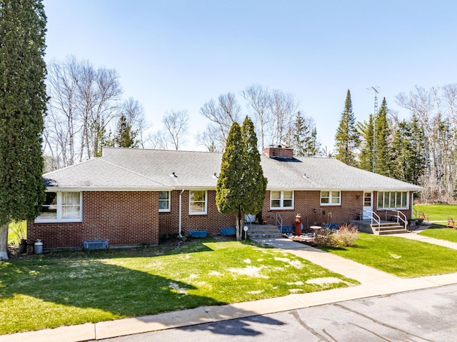 21895 County Road 8, Bovey, MN 55709 - view of front of house with brick siding, a front lawn, a chimney, and a shingled roof