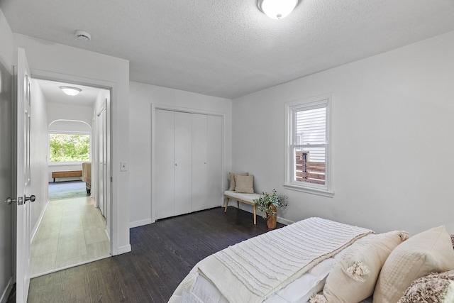 bedroom featuring wood finished floors, a textured ceiling, baseboards, and a closet