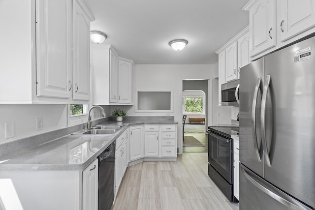 kitchen with black appliances, white cabinetry, a sink, and light stone countertops