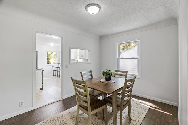 dining area with a textured ceiling, wood finished floors, and baseboards