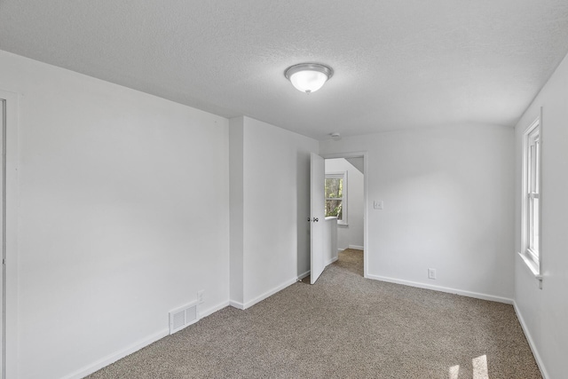 empty room featuring carpet, a textured ceiling, and baseboards
