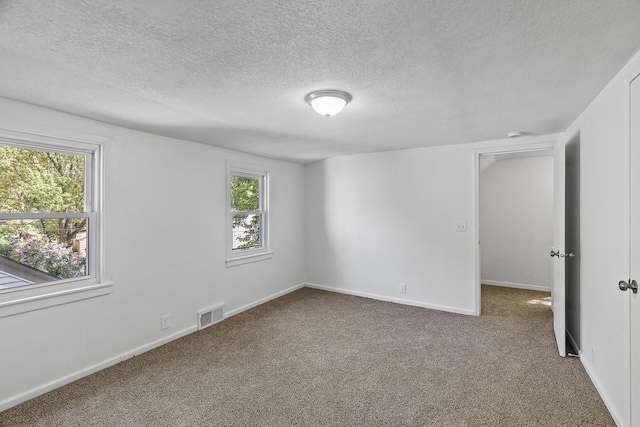 unfurnished room with a textured ceiling, carpet floors, and baseboards