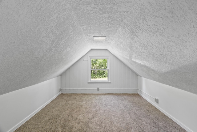 bonus room featuring a textured ceiling, lofted ceiling, baseboards, and carpet flooring