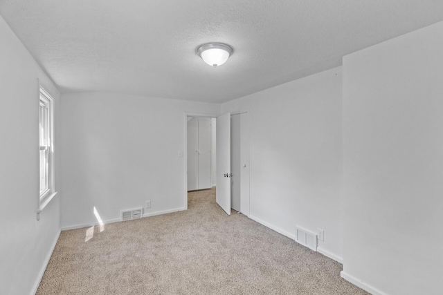 carpeted empty room featuring baseboards and a textured ceiling
