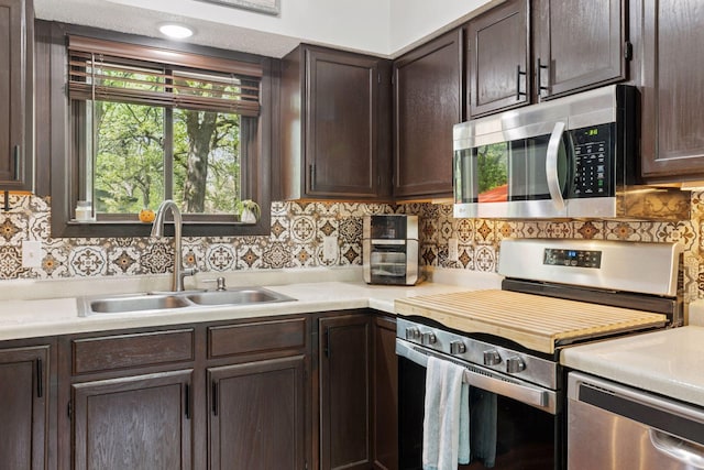 6242 Pecan St, North Branch, MN 55056 - kitchen with appliances with stainless steel finishes, a sink, dark brown cabinetry, light countertops, and tasteful backsplash