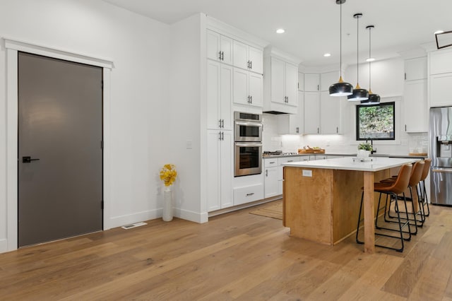 kitchen featuring appliances with stainless steel finishes, decorative backsplash, recessed lighting, white cabinets, and light wood-style floors