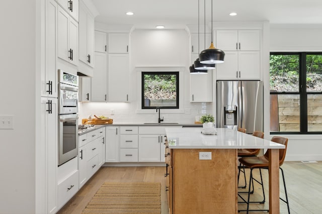 kitchen with a sink, light wood-style floors, a kitchen island, a breakfast bar area, and decorative backsplash
