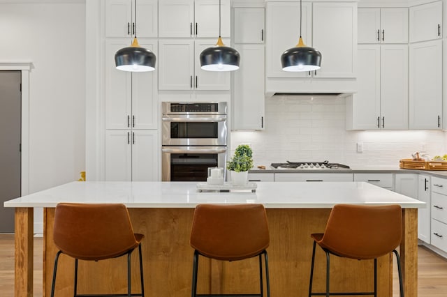 kitchen featuring appliances with stainless steel finishes, decorative backsplash, light countertops, and a breakfast bar