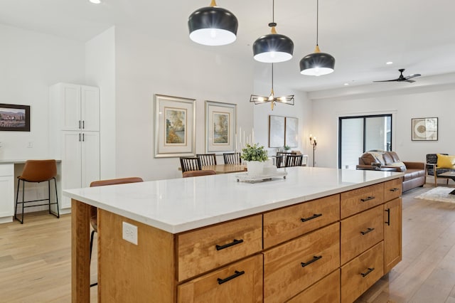 kitchen featuring light wood finished floors, open floor plan, recessed lighting, a breakfast bar, and pendant lighting