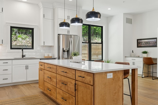 kitchen with stainless steel refrigerator with ice dispenser, a sink, light wood-style floors, recessed lighting, and tasteful backsplash